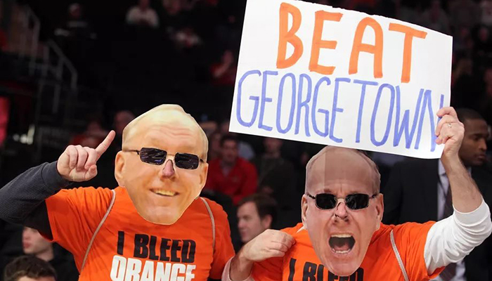 Two fans wearing Boeheim masks with "I bleed Orange" t-shirts hold a sign that says "Beat Georgetown"